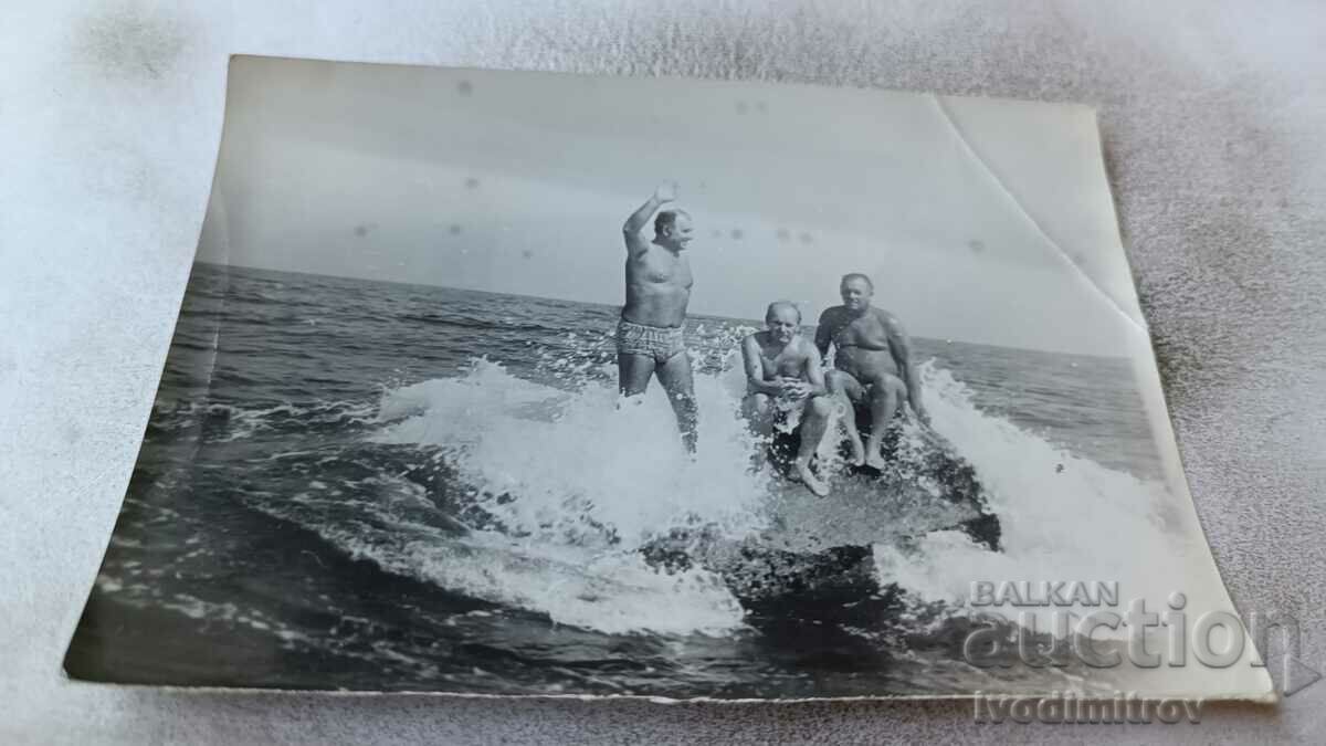 Foto Trei bărbați în costume de baie pe o stâncă în mare