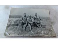 Photo Three men in swimsuits on a rock by the sea