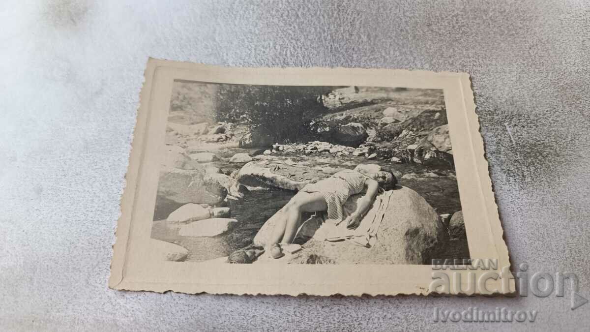 Φωτογραφία Νεαρό κορίτσι ξαπλωμένο σε έναν βράχο πάνω από τη θάλασσα