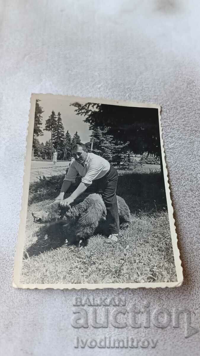 Снимка Мъж върху препарирана мечка