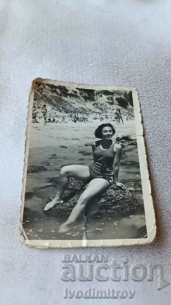 Fotografie Fată tânără în costum de baie de epocă stând pe o stâncă în mare