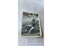 Снимка Младо момиче с ретро бански седнала на скала в морето