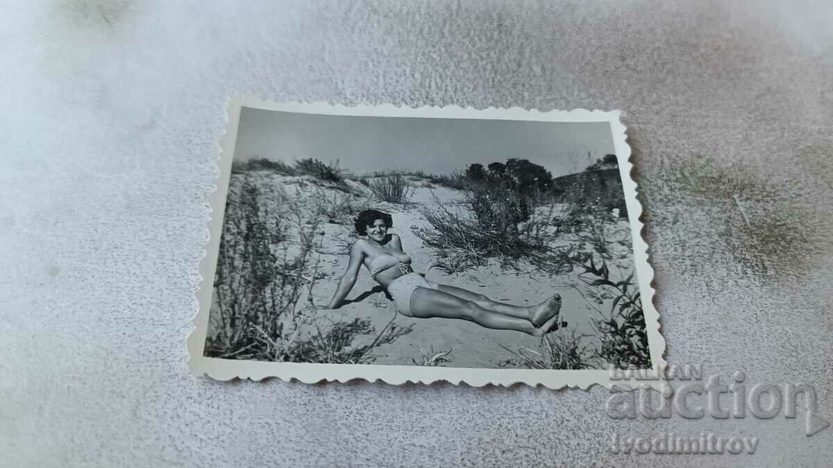 Φωτογραφία Νεαρό κορίτσι με μαγιό που κάθεται σε έναν αμμόλοφο