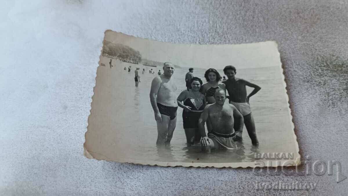 Foto Trei bărbați și două femei pe plajă