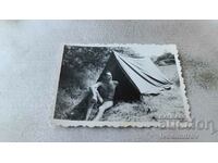 Снимка Млад мъж по бански седнал пред палатка