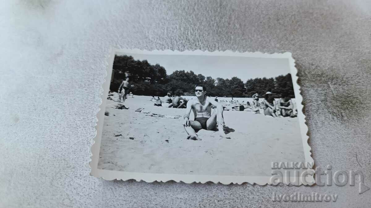 Foto Bărbat în costum de baie cu ochelari de soare pe plajă
