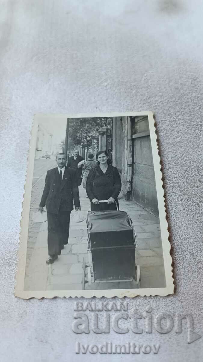 Photo Sofia A man and a woman with a retro baby carriage on the sidewalk