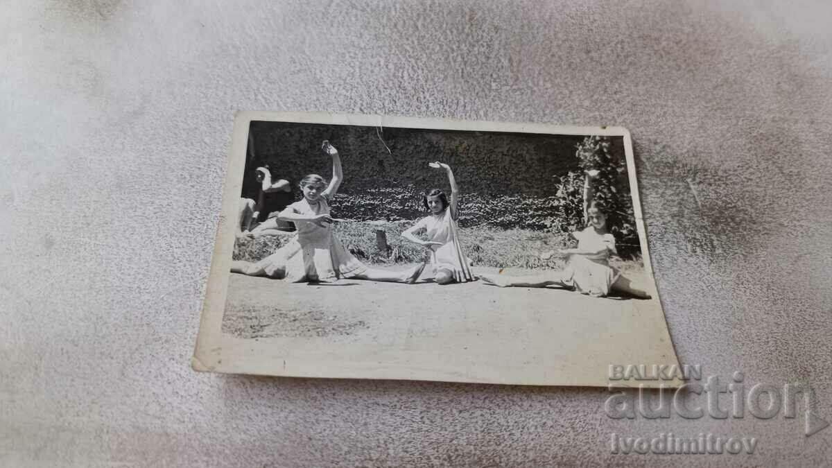 Imagine Trei fete tinere în rochii albe făcând shtpagat