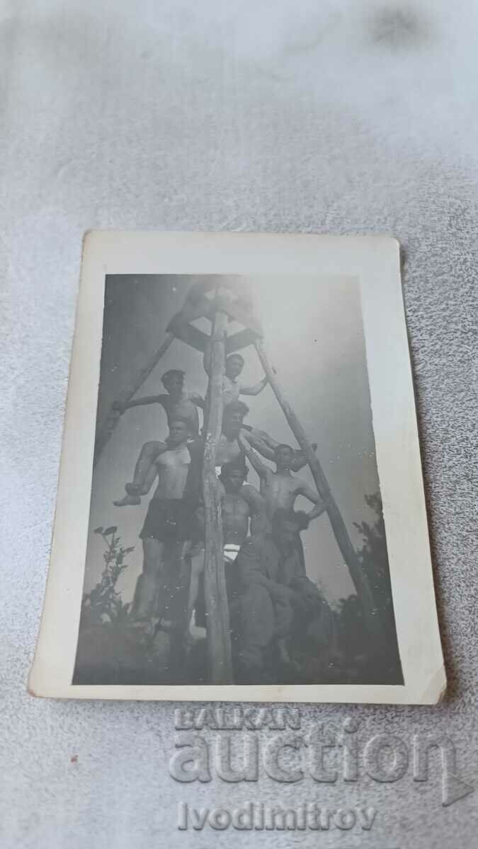 Снимка Млади мъже с къси панталони на дървена пирамида