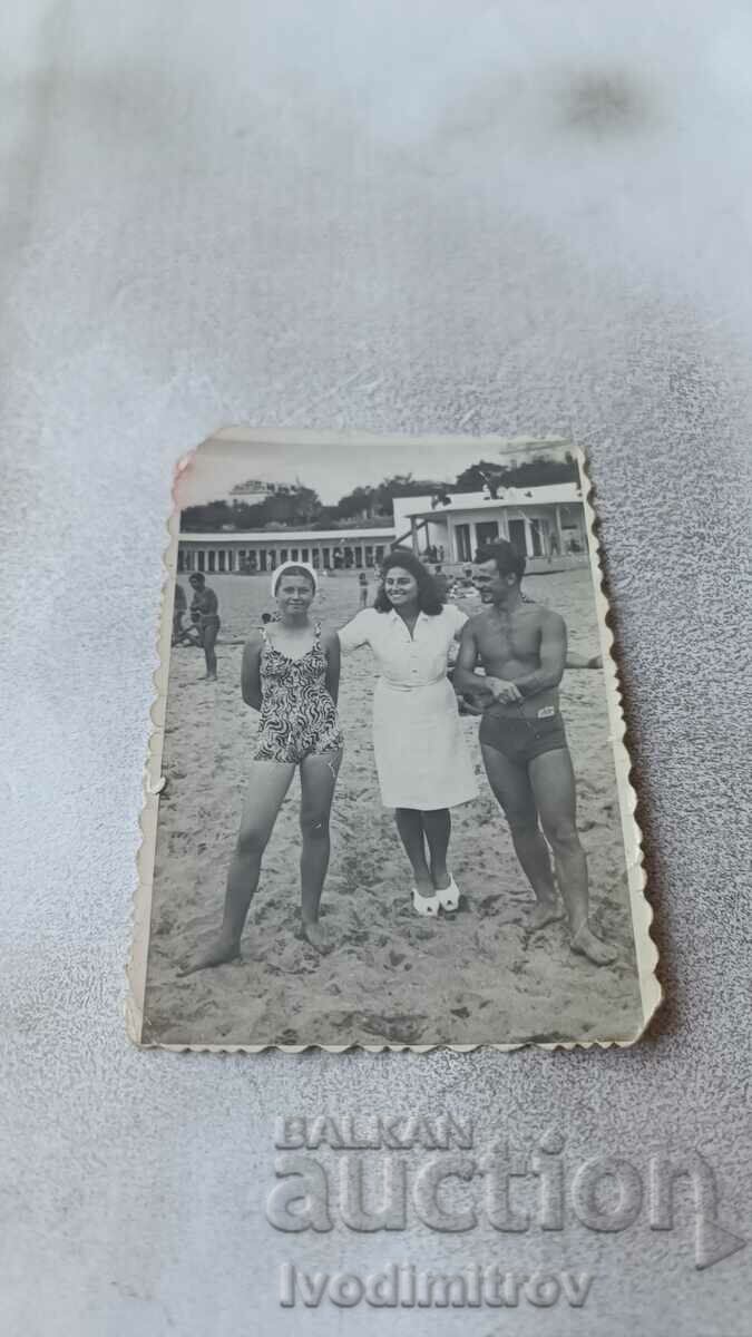 Photo A man and two young women on the beach