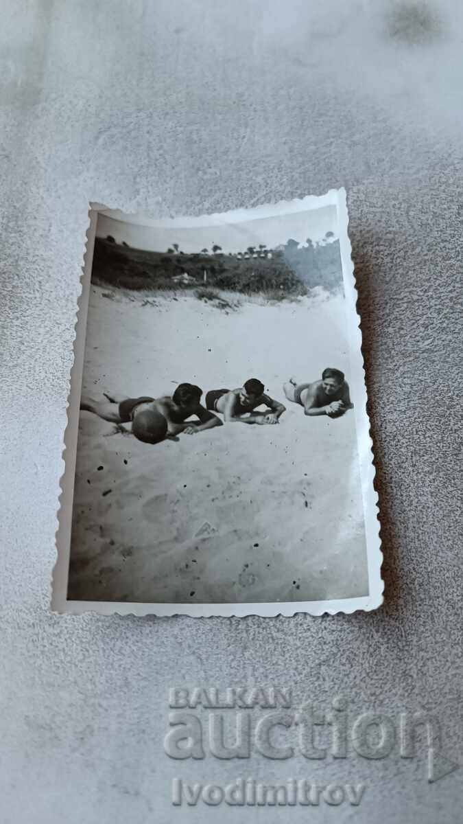 Foto Trei bărbați întinși pe plajă