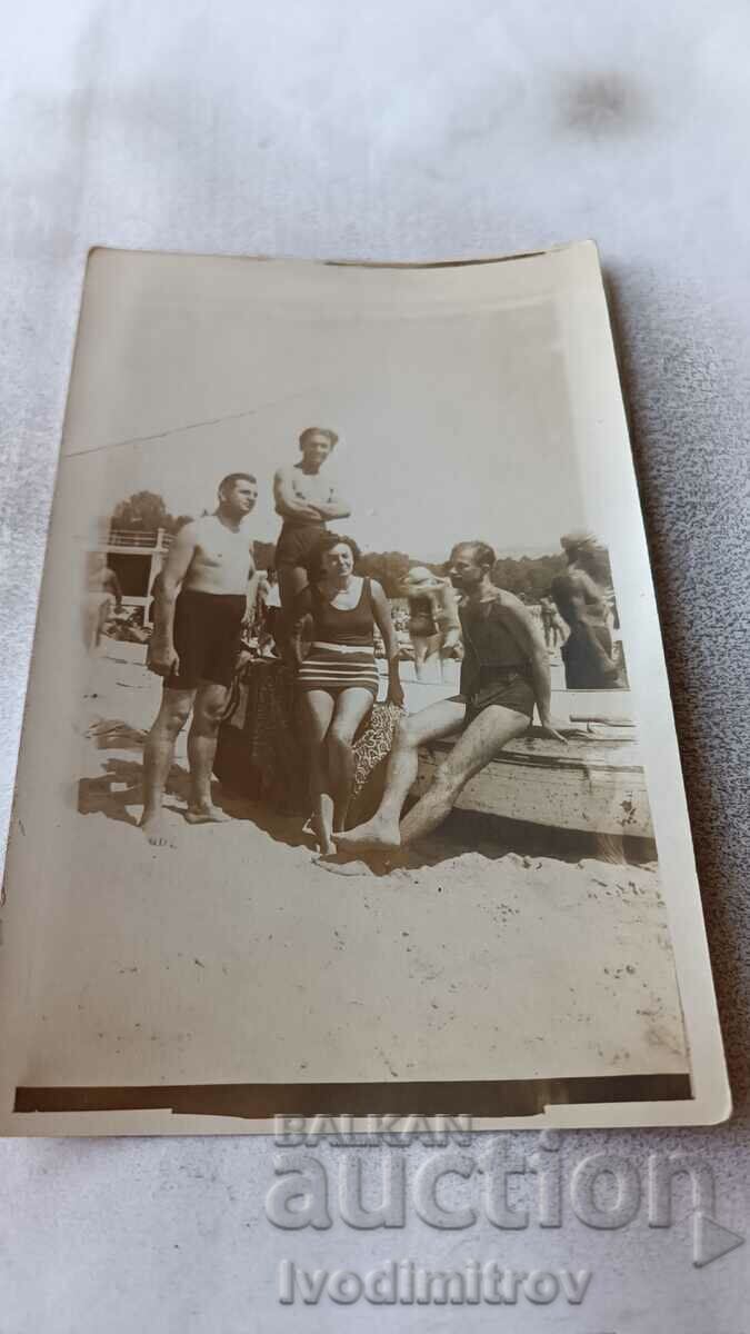 Photo Three men and a woman in vintage swimsuits on the beach