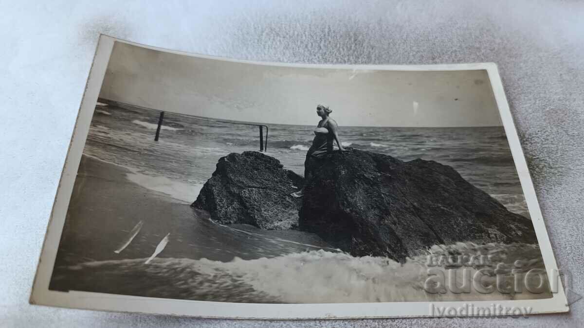 Foto Fată tânără lângă o stâncă pe malul mării
