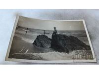 Photo Young girl next to a rock on the seashore