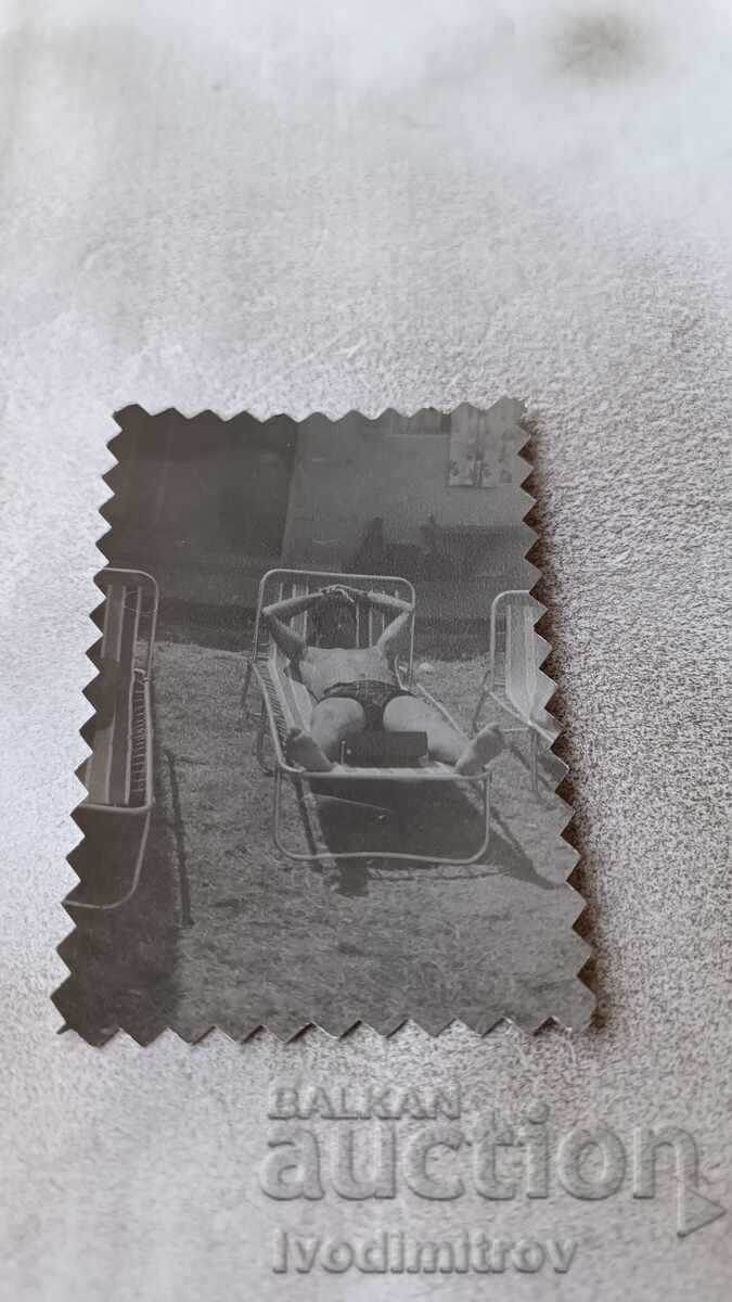 Φωτογραφία Ένας νεαρός άνδρας με μαγιό σε ένα κρεβάτι κάμπινγκ