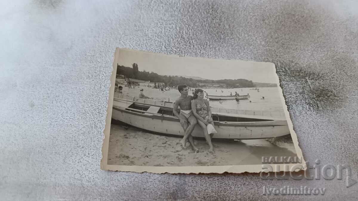 Photo A young man and a young woman next to a wooden boat on the shore