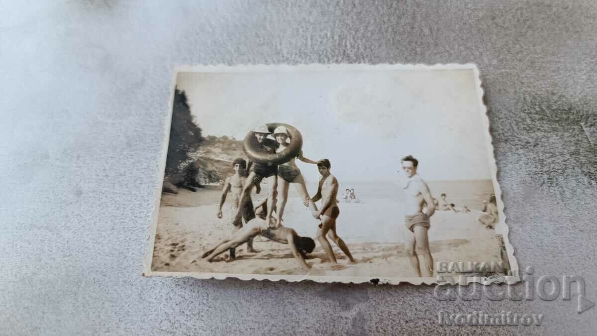 Φωτογραφία Νέοι άνδρες και γυναίκες φτιάχνουν μια πυραμίδα στην παραλία