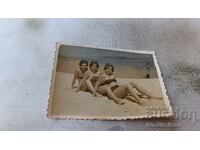 Φωτογραφία Τρεις νεαρές γυναίκες που κάθονται στην άμμο 1960