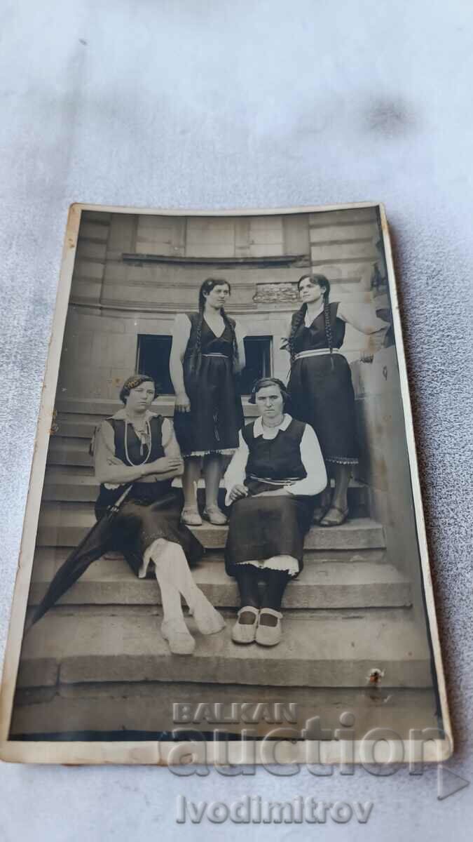 Photo Four young girls in traditional clothing on stairs