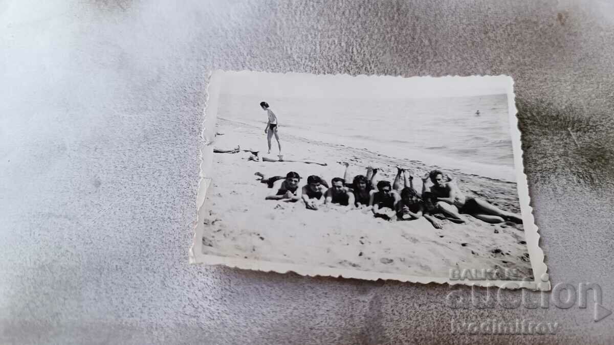 Photo Young men and women lying on their stomachs on the sand