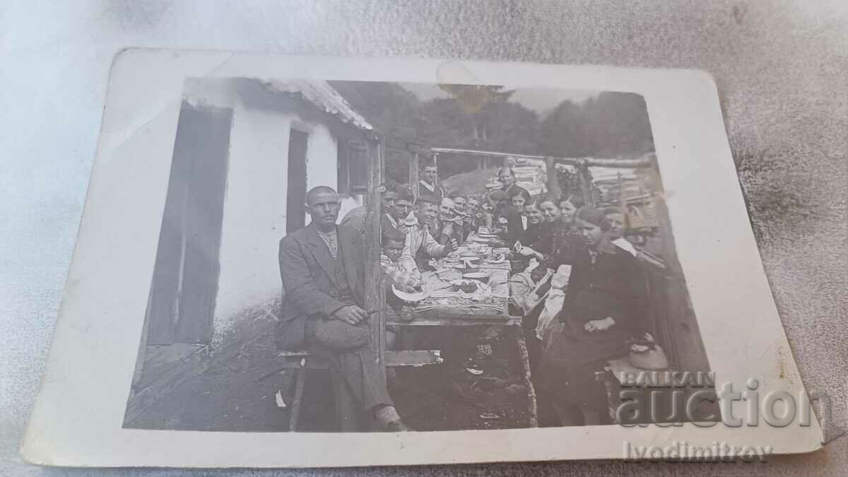 Photo Men women and children at a long wooden table