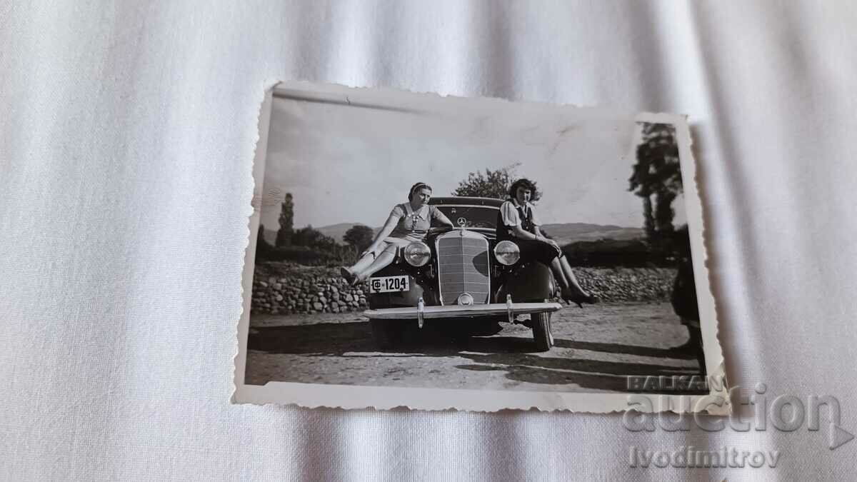 Fotografie Două fete tinere stând pe un Mercedes Sf 1204 de epocă