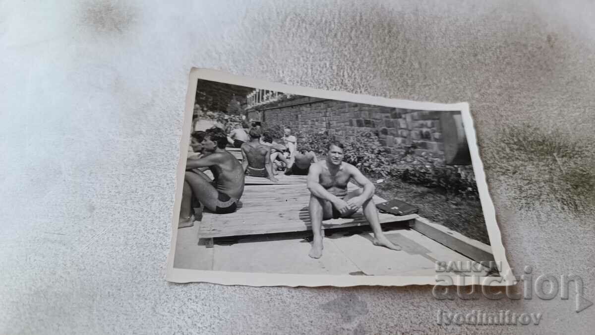 Photo Men in swimsuits sitting on a wooden platform