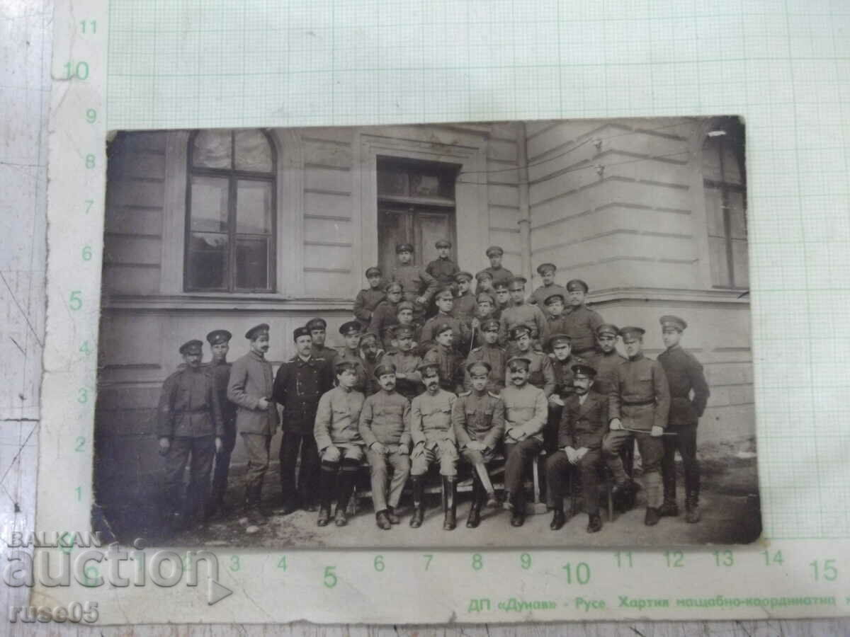 Fotografie veche a unui grup de bărbați în uniformă în fața unei clădiri