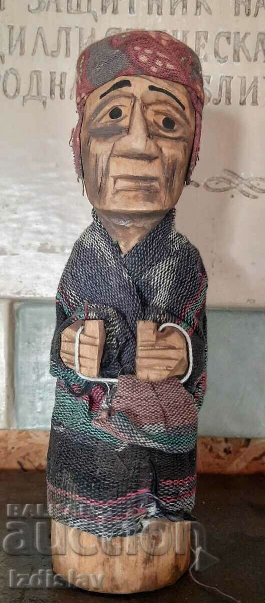 A small wooden doll in the shape of a man with a bag