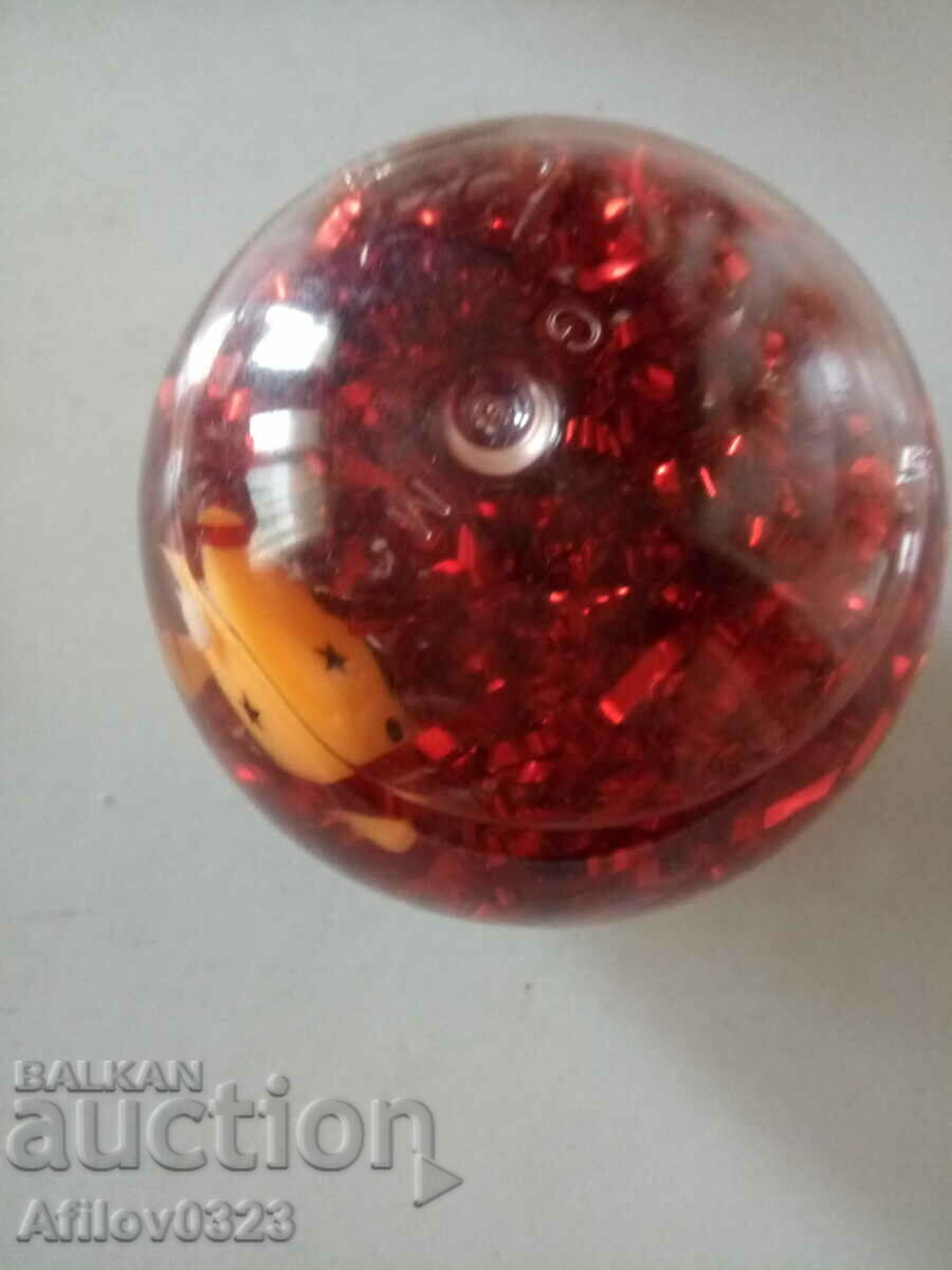 A pacifier ball with glittering ribbons and figures floating in it