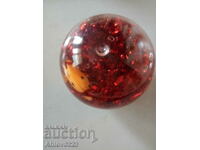 A pacifier ball with glittering ribbons and figures floating in it