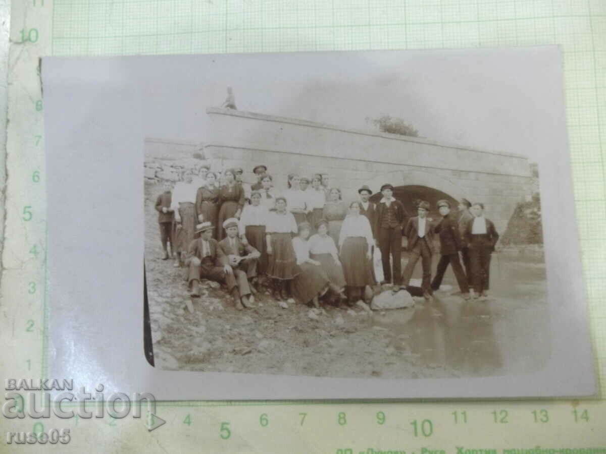 Old photo of a group of young people on the river in front of the bridge