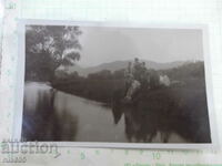 An old photo of a group of young people sitting on the bank by the river