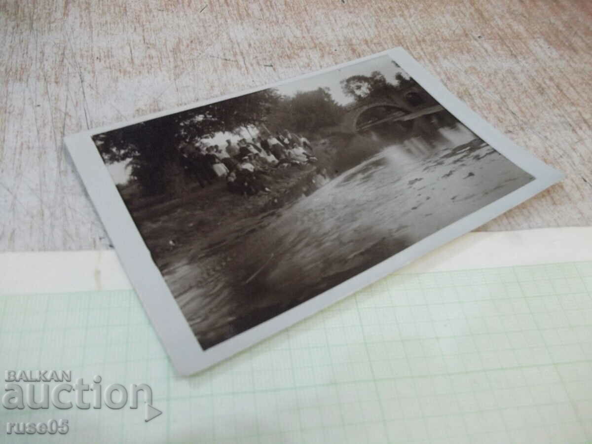 Δημοπρασία Μια παλιά φωτογραφία νεαρών ανθρώπων που κάθονται στην όχθη μπροστά από τη γέφυρα