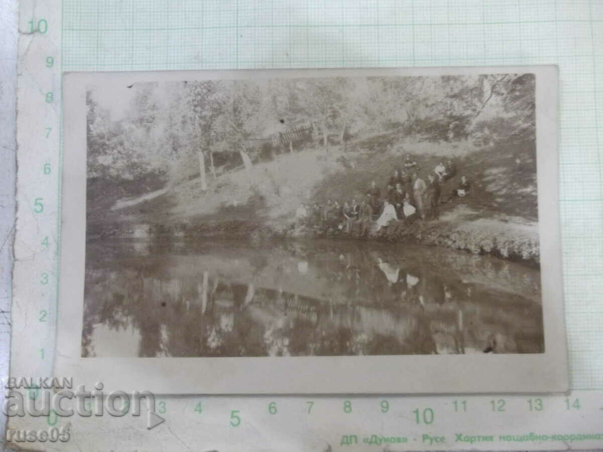 Old photo of a group on the steep bank of the river