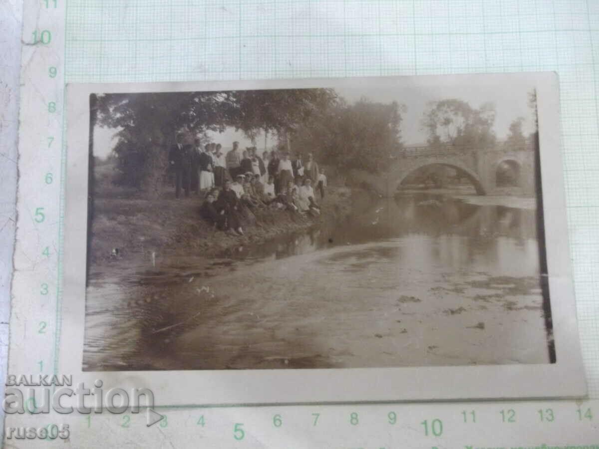 An old photo of a group of young people by the river bridge