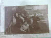 An old photo of four women and a man in front of a fence