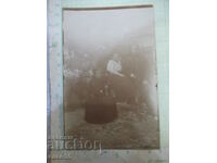 An old photo of two women and a man in front of a fence