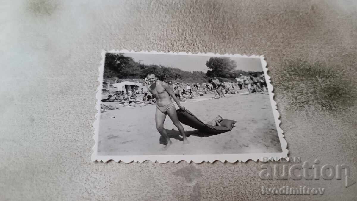 Photo Man pulling an inflatable mattress on the beach