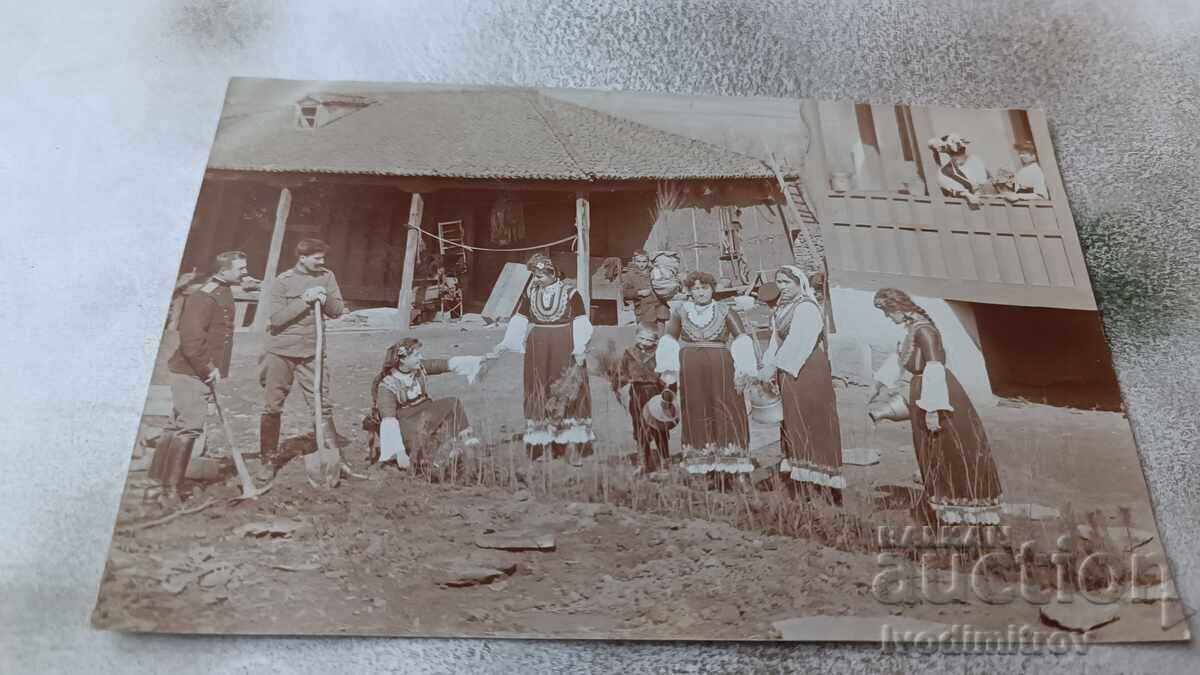 Photo Two officers and women in folk costumes planting a hedge Photo Two officers and women in folk costumes planting a hedge