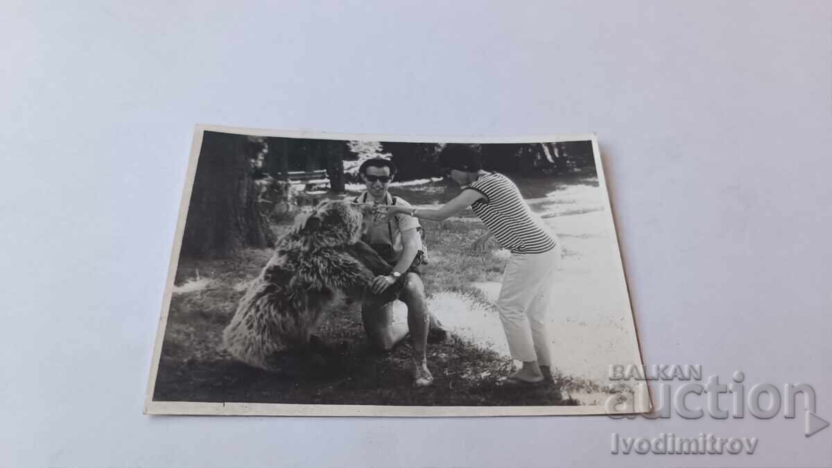 Photo Man and woman next to a bear in the park Photo Man and woman next to a bear in the park
