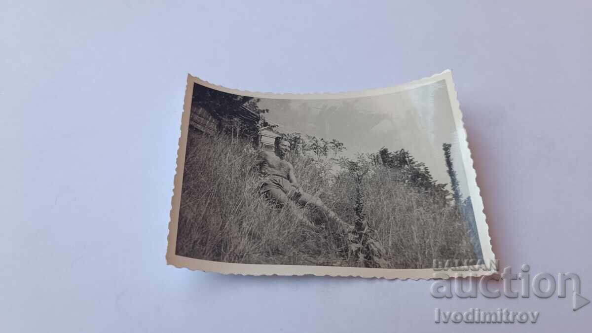 Photo of a man naked to the waist sitting on the grass Photo of a man naked to the waist sitting on the grass