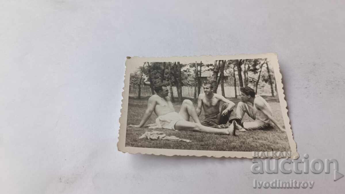 Fotografie cu trei tineri bărbați stând pe iarbă