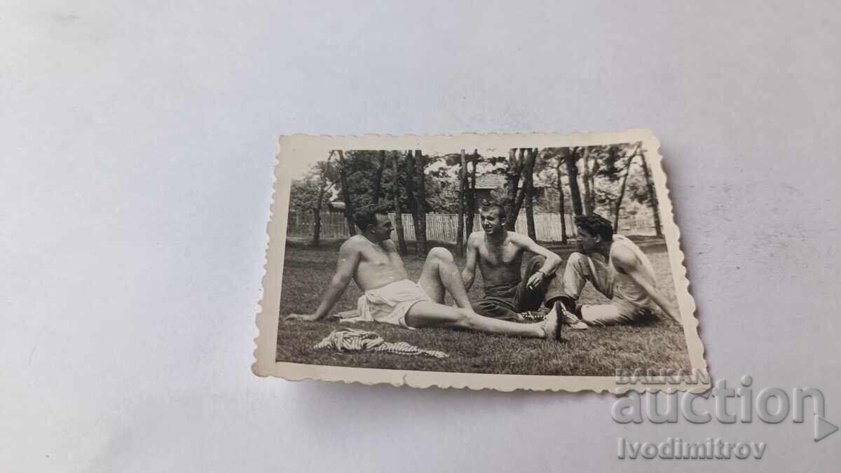 Fotografie cu trei tineri bărbați stând pe iarbă