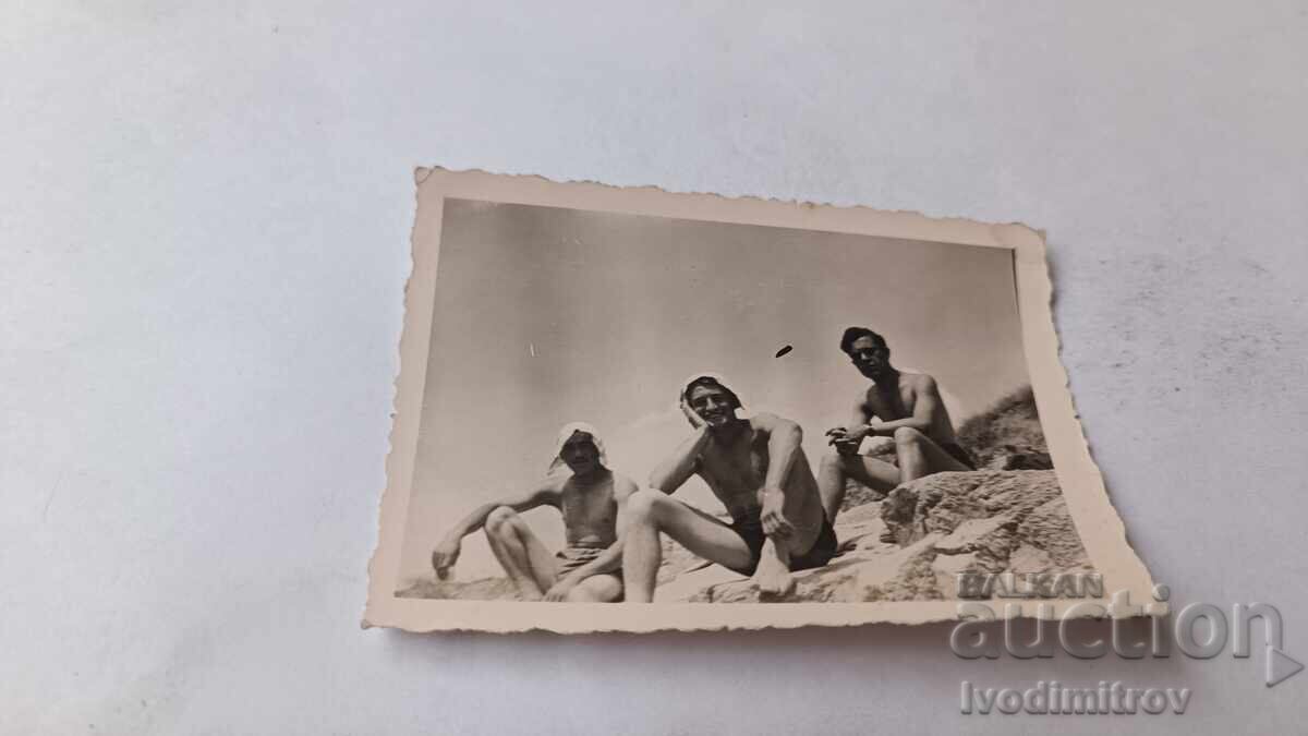 Photo: Three young men sitting on a rock
