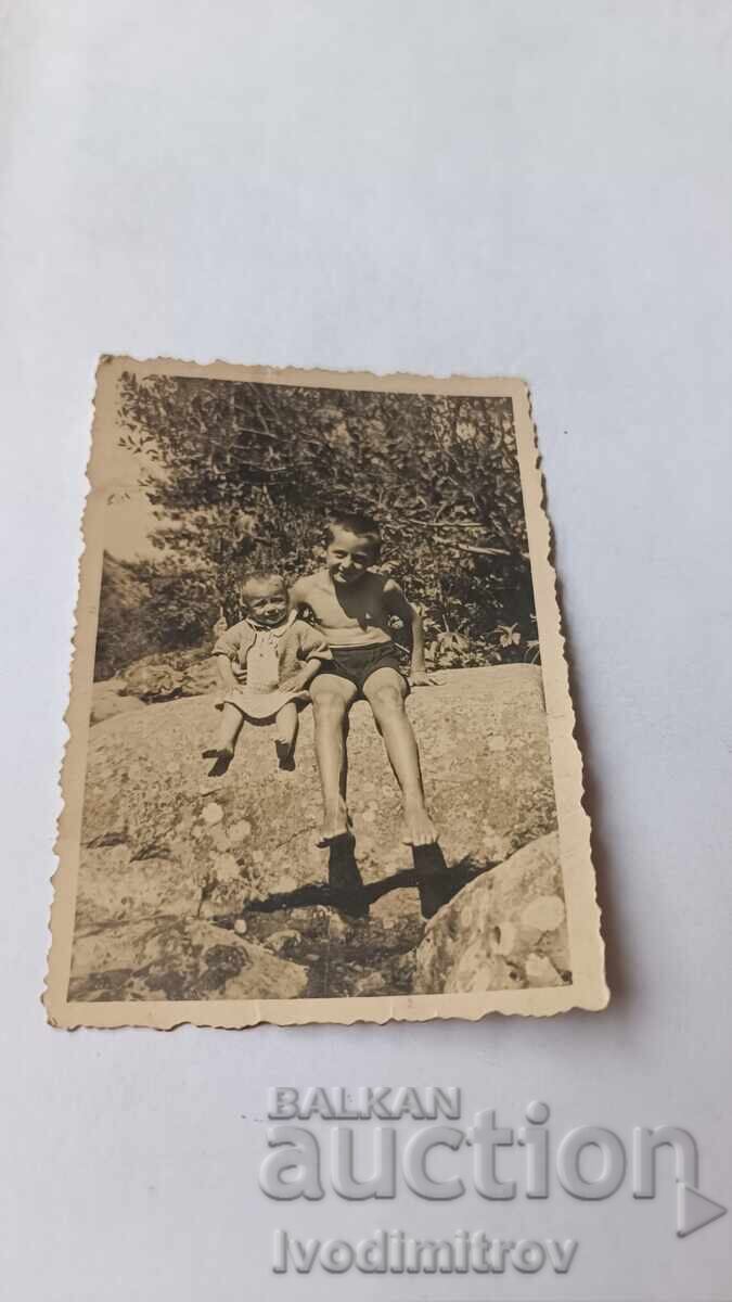 Fotografie cu băiat și bebeluș șezând pe o piatră mare