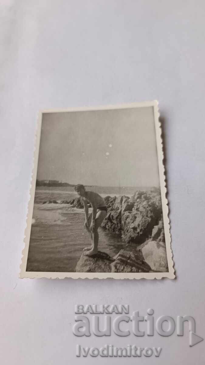 Fotografie Tânăr pe stâncă deasupra mării Fotografie Tânăr pe stâncă deasupra mării