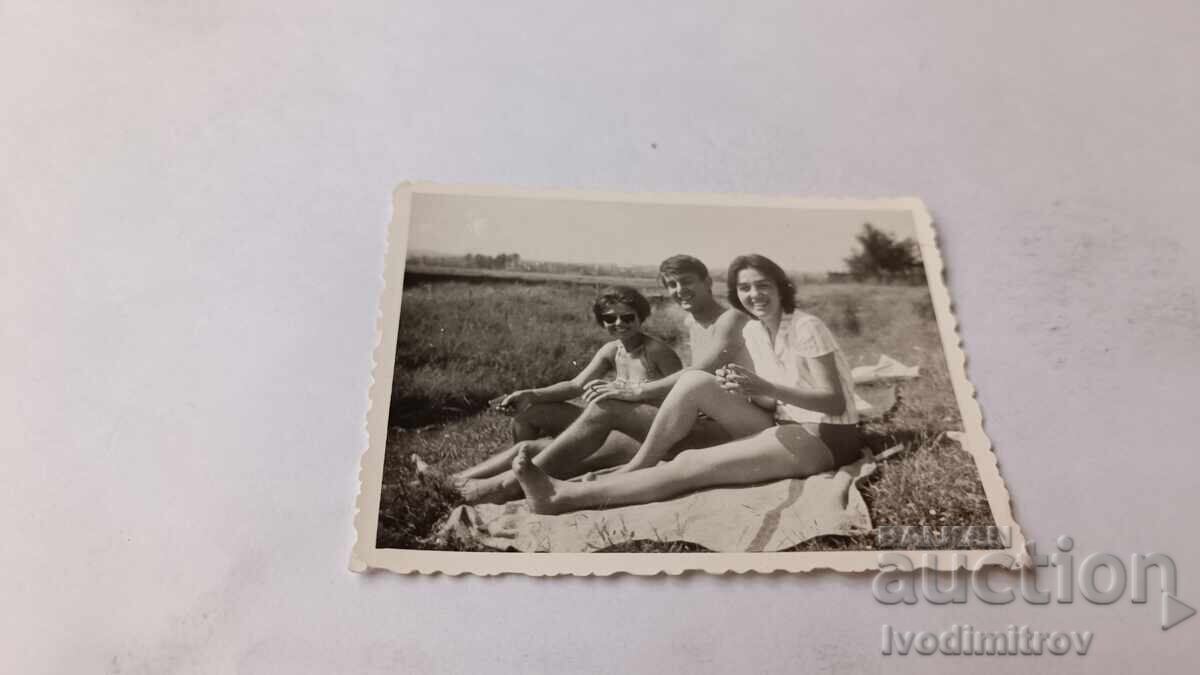 Φωτογραφία Νέου και δύο κοριτσιών καθισμένων στο γρασίδι