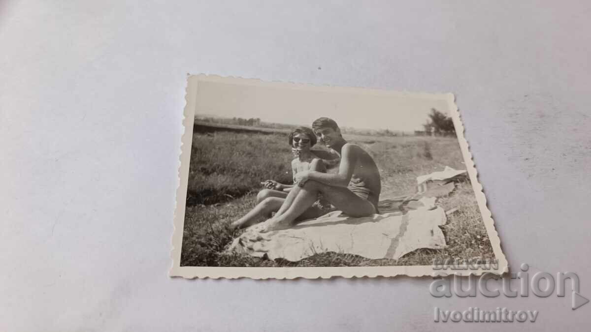 Fotografie: Tineri, băiat și fată, stând pe iarbă