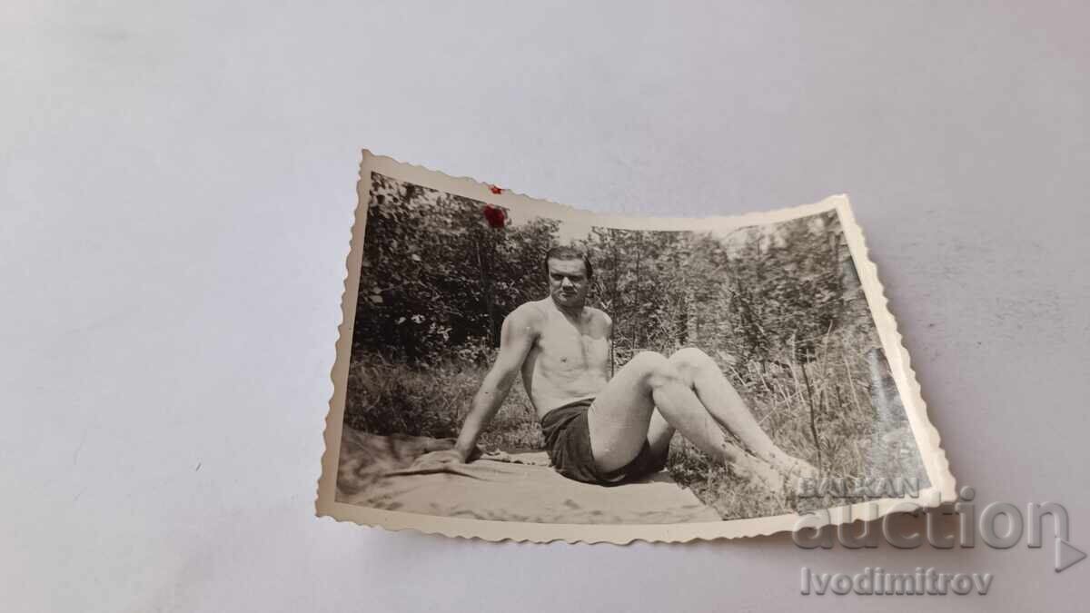 Φωτογραφία Νέος άνδρας με κοντό παντελόνι να κάθεται σε βράχο